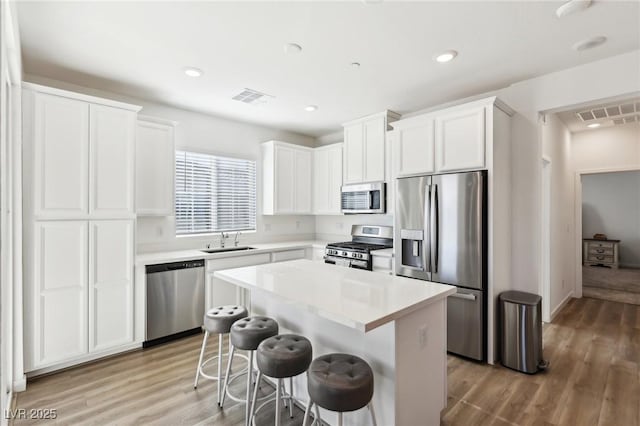 kitchen featuring white cabinets, a kitchen island, sink, and appliances with stainless steel finishes