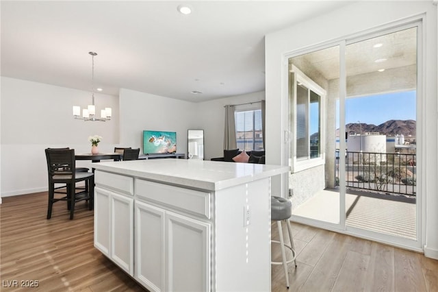 kitchen featuring light hardwood / wood-style flooring, a notable chandelier, a center island, white cabinetry, and hanging light fixtures