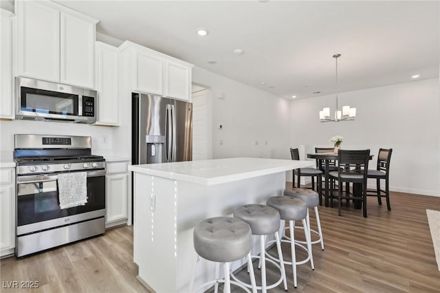 kitchen with white cabinetry, a center island, stainless steel appliances, and decorative light fixtures