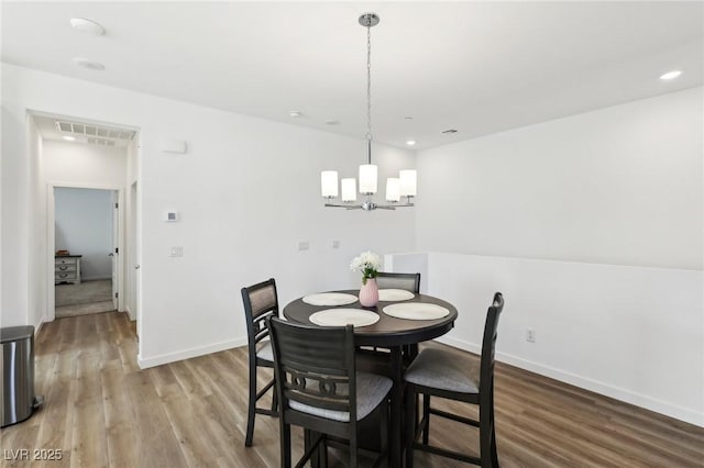 dining area with hardwood / wood-style floors and an inviting chandelier