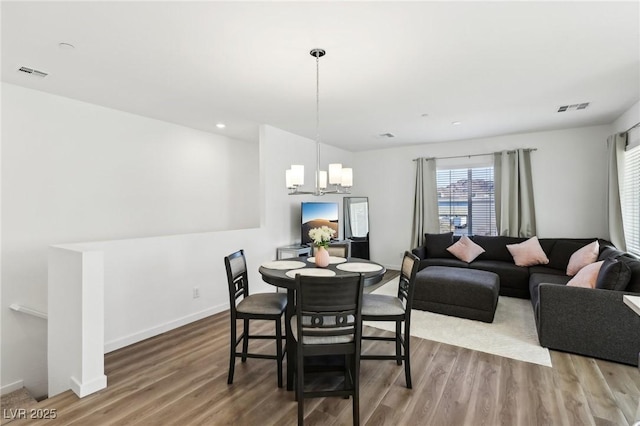 dining area with hardwood / wood-style flooring and an inviting chandelier