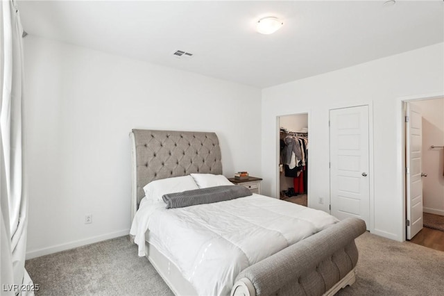 bedroom featuring a walk in closet, ensuite bathroom, a closet, and carpet floors