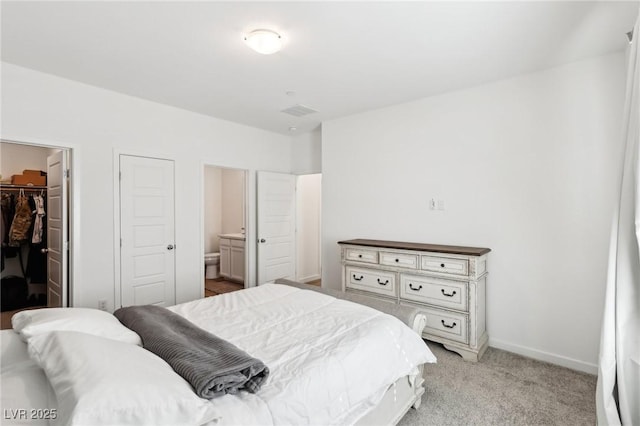 bedroom with connected bathroom, a spacious closet, a closet, and light carpet