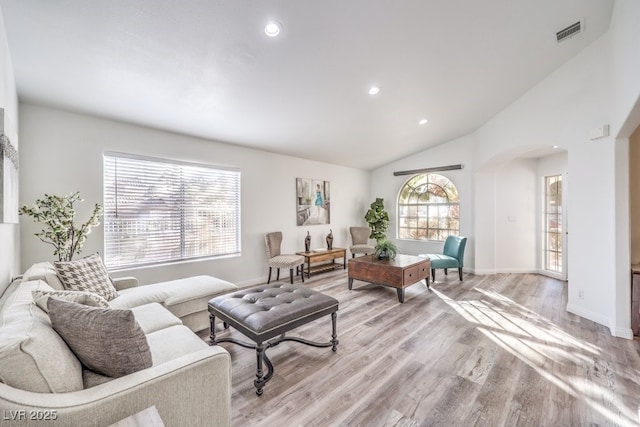 living room featuring lofted ceiling and light hardwood / wood-style floors