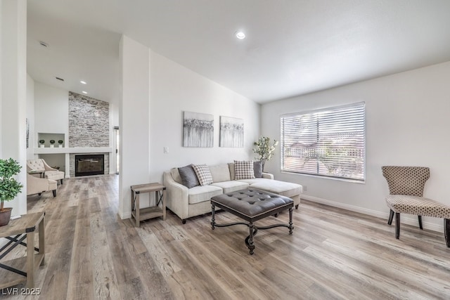 living room with light hardwood / wood-style flooring, lofted ceiling, and a fireplace