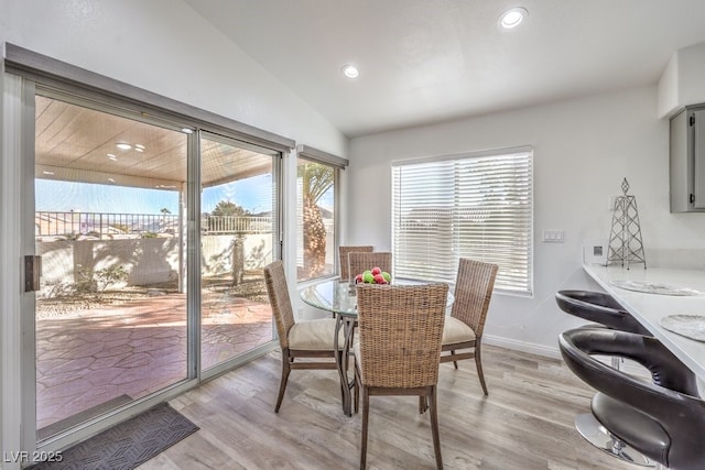 dining area featuring vaulted ceiling and light hardwood / wood-style flooring