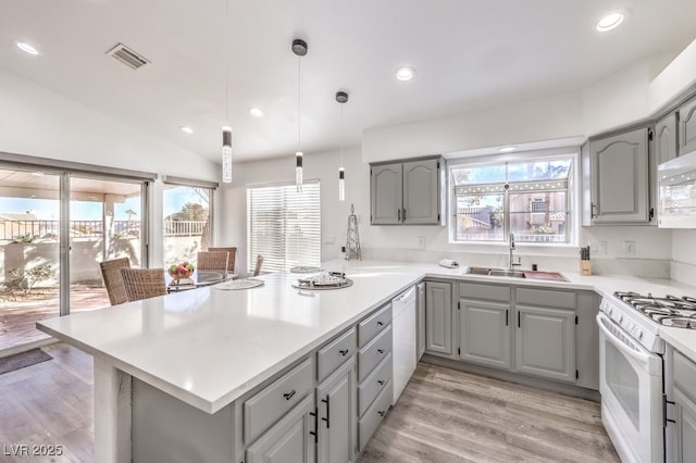 kitchen with white appliances, vaulted ceiling, decorative light fixtures, light hardwood / wood-style floors, and sink