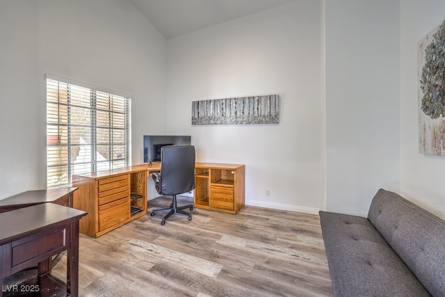 office area with light hardwood / wood-style flooring and high vaulted ceiling