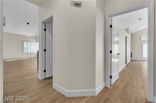 hall featuring light wood-type flooring and vaulted ceiling