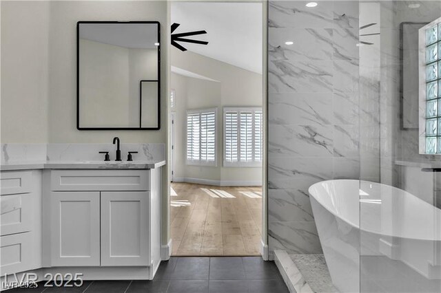 bathroom with tile patterned flooring, vanity, tile walls, and independent shower and bath