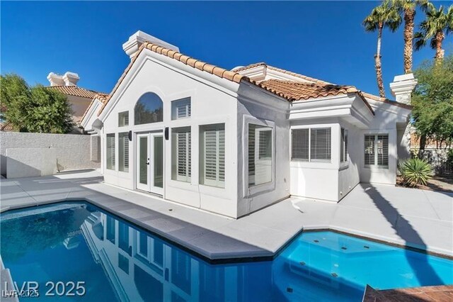 rear view of property featuring a fenced in pool, a patio, and french doors