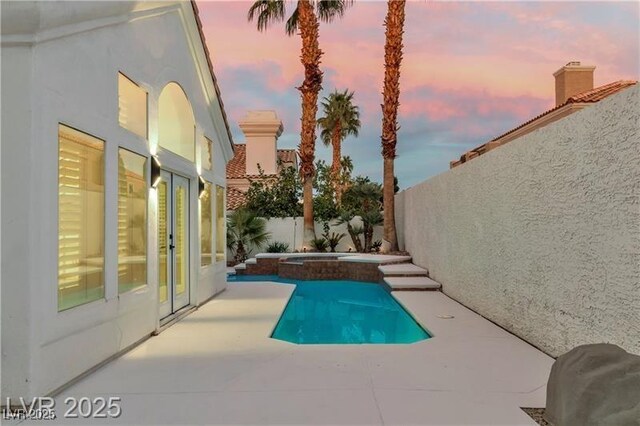 pool at dusk featuring a patio