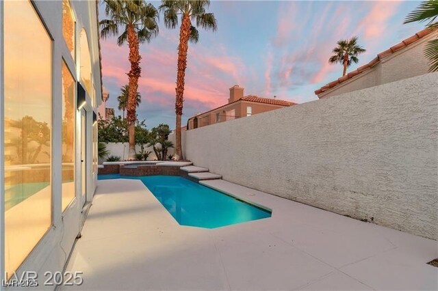 pool at dusk with a patio area