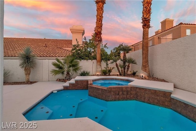 pool at dusk with an in ground hot tub