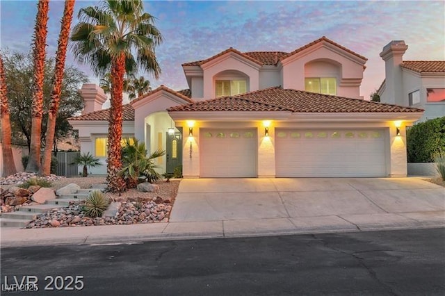 mediterranean / spanish-style house featuring a garage, a tiled roof, concrete driveway, and stucco siding