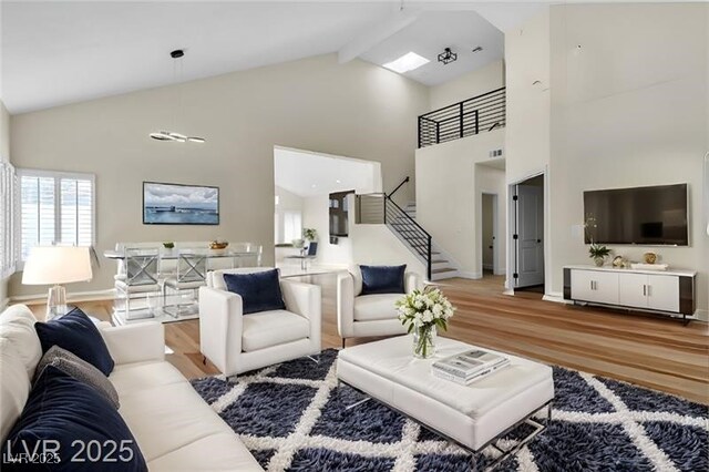 living room with hardwood / wood-style floors, high vaulted ceiling, and beam ceiling