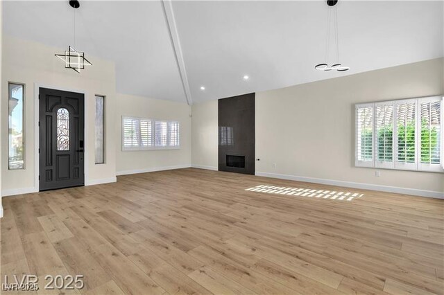 foyer entrance with a fireplace, light hardwood / wood-style flooring, and vaulted ceiling