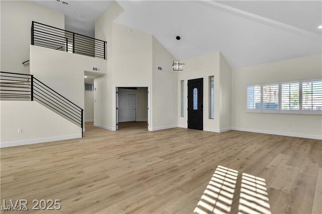 unfurnished living room featuring high vaulted ceiling and light hardwood / wood-style flooring