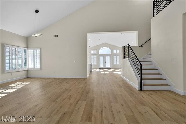 unfurnished living room featuring light hardwood / wood-style floors, high vaulted ceiling, and plenty of natural light