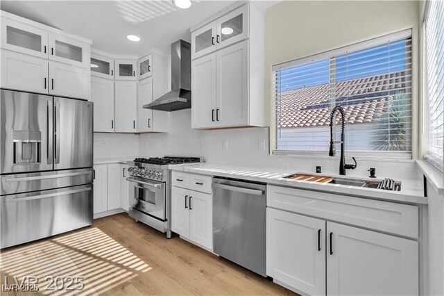 kitchen featuring white cabinetry, sink, wall chimney range hood, and stainless steel appliances