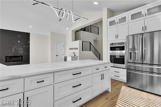 kitchen with white cabinetry, a high end fireplace, and appliances with stainless steel finishes