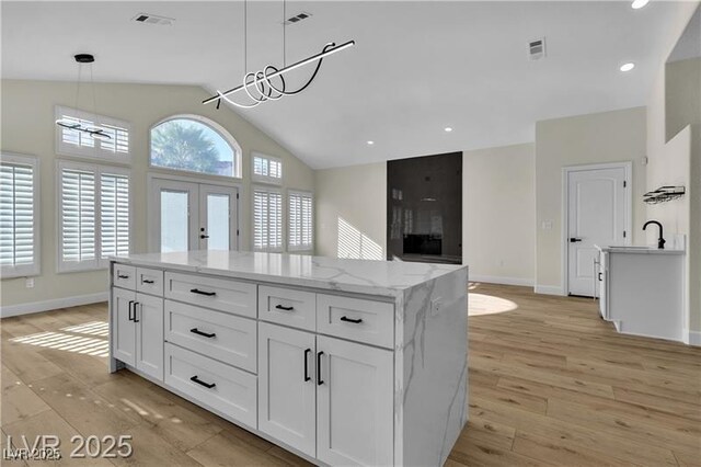 kitchen with white cabinets, pendant lighting, light wood-type flooring, and a kitchen island