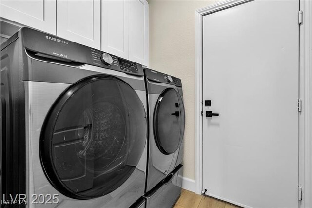 laundry area featuring washer and clothes dryer, cabinets, and light hardwood / wood-style floors