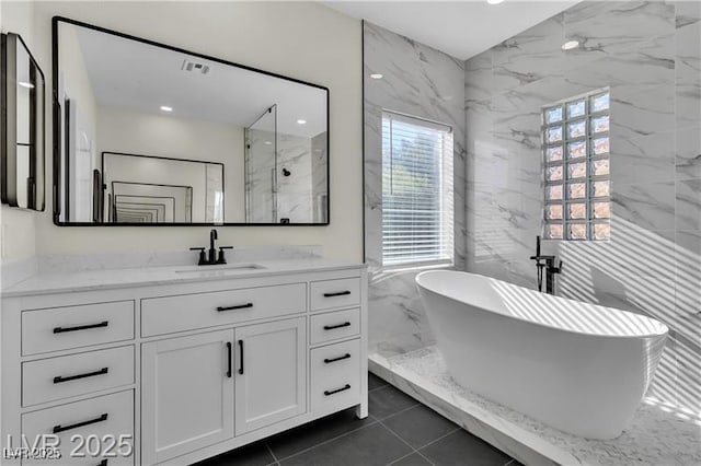 bathroom featuring tile patterned floors, separate shower and tub, vanity, and tile walls