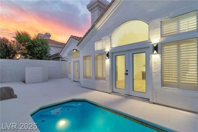 pool at dusk with a patio and french doors