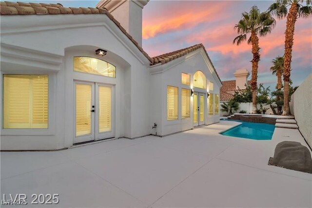 back house at dusk with a patio and french doors