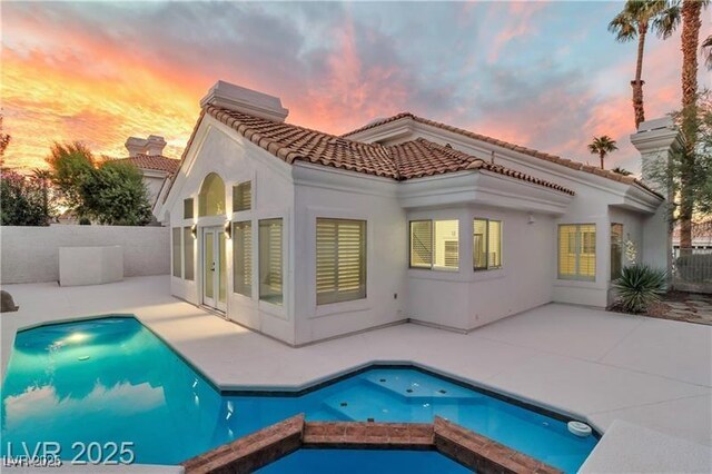 back house at dusk with a fenced in pool and a patio area