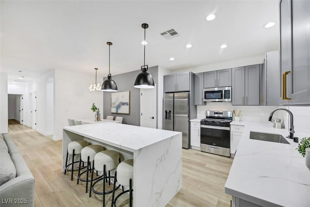 kitchen with light stone counters, a kitchen island, sink, and stainless steel appliances