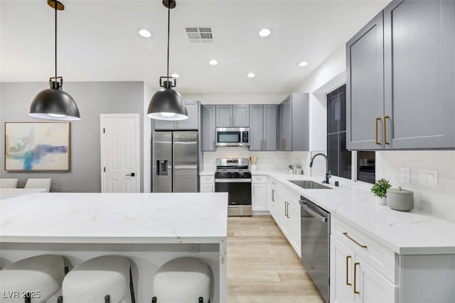 kitchen with pendant lighting, stainless steel appliances, gray cabinets, and sink