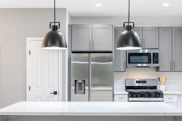 kitchen featuring light stone counters, decorative light fixtures, gray cabinets, decorative backsplash, and appliances with stainless steel finishes