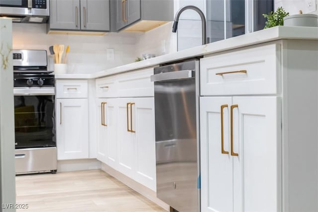 kitchen with tasteful backsplash, light hardwood / wood-style flooring, white cabinets, and stainless steel appliances