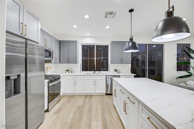 kitchen featuring light hardwood / wood-style flooring, decorative backsplash, decorative light fixtures, light stone counters, and stainless steel appliances