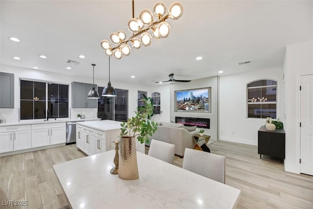 dining area featuring ceiling fan with notable chandelier, light wood-type flooring, and sink