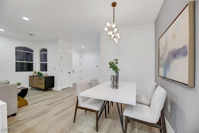 dining space with a notable chandelier and light hardwood / wood-style flooring