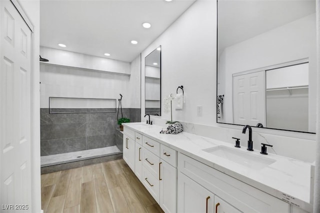 bathroom with tiled shower, wood-type flooring, and vanity