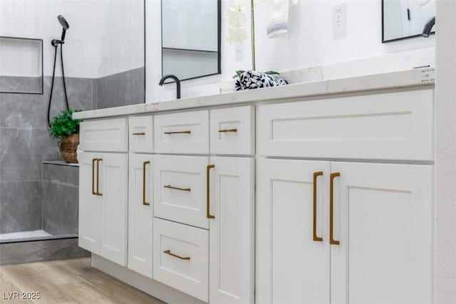 bathroom featuring hardwood / wood-style flooring, vanity, and tiled shower