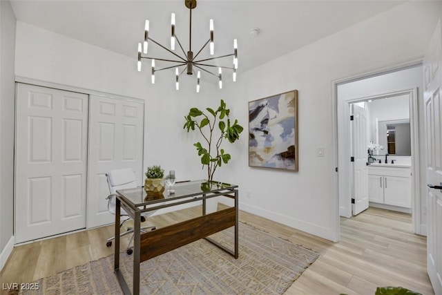 office space featuring light wood-type flooring, sink, and an inviting chandelier