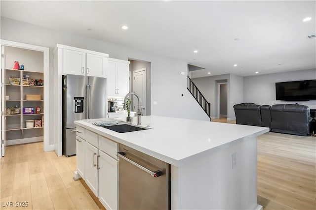 kitchen featuring sink, an island with sink, white cabinets, and appliances with stainless steel finishes