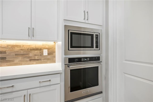 kitchen featuring backsplash, white cabinets, and stainless steel appliances