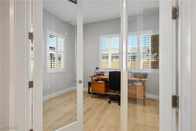 home office with a healthy amount of sunlight and light hardwood / wood-style flooring