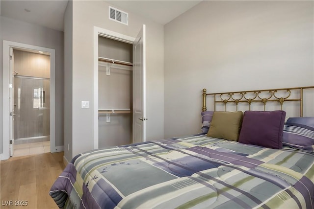 bedroom with connected bathroom, light hardwood / wood-style floors, and a closet