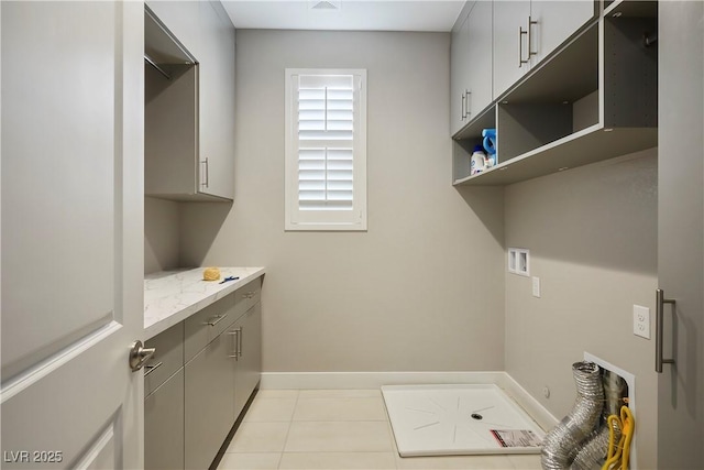 clothes washing area with washer hookup, light tile patterned flooring, and cabinets