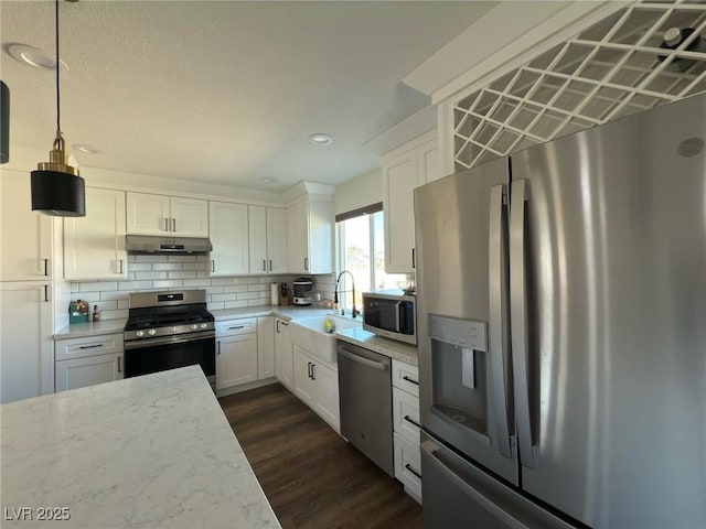 kitchen with white cabinetry, tasteful backsplash, dark hardwood / wood-style floors, pendant lighting, and appliances with stainless steel finishes