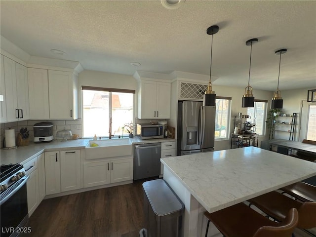 kitchen with stainless steel appliances, white cabinetry, a kitchen island, and sink