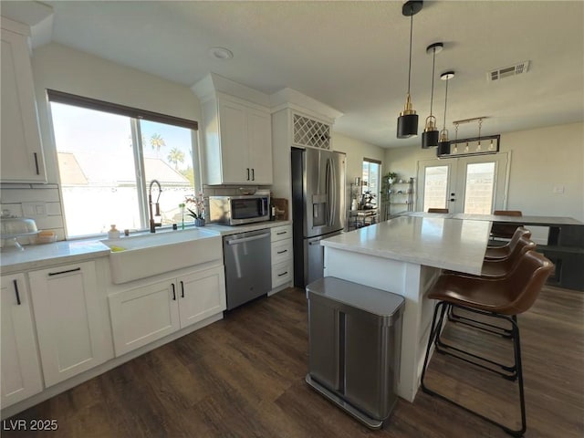 kitchen with white cabinetry, sink, hanging light fixtures, and appliances with stainless steel finishes