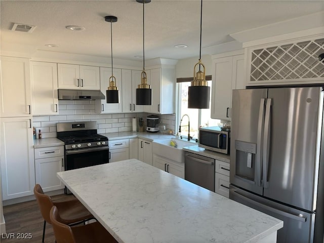 kitchen with tasteful backsplash, stainless steel appliances, sink, pendant lighting, and white cabinetry